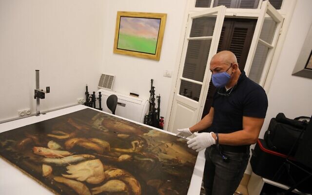 Gaby Maamary, spécialiste libanais de la conservation des œuvres d'art, examine un tableau du XVIIe siècle de la peintre italienne Elena Recco, endommagé lors de l'explosion du port de Beyrouth, dans son atelier de la capitale, le 17 septembre 2020. (ANWAR AMRO / AFP)