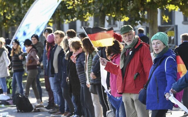 Des citoyens participent à une chaîne humaine pour protester contre le port du masque et les restrictions liés à la pandémie de coronavirus à Constance, dans l'ouest de l'Allemagne, le 3 octobre 2020. (SEBASTIEN BOZON / AFP)