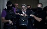 L'ancien député et chef du parti Aube dorée, Nikolaos Michaloliakos escorté par la police, à Athènes, le 28 septembre 2013. (Crédit : Angelos Tzortzinis/AFP)
