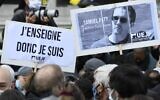 Des manifestants tenant une pancarte indiquant « J'enseigne donc je suis » et un portrait du professeur d'histoire Samuel Paty alors qu'ils se rassemblent place de la République à Paris, le 18 octobre 2020, deux jours après que l'homme a été décapité par un terroriste abattu par les policiers. (Crédit : Bertrand Guay/AFP)