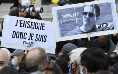 Des manifestants tenant une pancarte indiquant « J'enseigne donc je suis » et un portrait du professeur d'histoire Samuel Paty alors qu'ils se rassemblent place de la République à Paris, le 18 octobre 2020, deux jours après que l'homme a été décapité par un terroriste abattu par les policiers. (Crédit : Bertrand Guay/AFP)