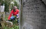 Un bénévole nettoie l'ancien cimetière juif de Waehring, à Vienne, le 18 octobre 2020. (Crédit : ALEX HALADA / AFP)