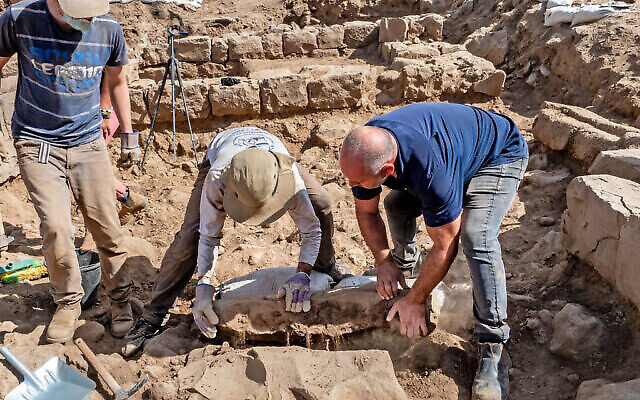 Des employés soulèvent la pierre de bornage découverte lors de fouilles de l'Autorité israélienne des Antiquités à Nafah, sur le plateau du Golan. (Crédit : Assaf Peretz/Autorité israélienne des Antiquités)