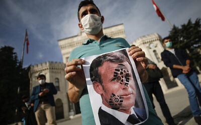 Un homme tient une photographie du président français Emmanuel Macron, piétinée lors d'une manifestation contre la France à Istanbul, le 25 octobre 2020. (Crédit : AP Photo/Emrah Gurel)