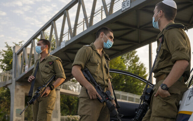 Des soldats israéliens portent le masque à un barrage routier à Tel Aviv, pendant le confinement national dû à la crise du coronavirus, le 19 septembre 2020 (Crédit : AP Photo/Ariel Schalit) Des soldats israéliens portent le masque à un barrage routier à Tel Aviv, pendant le confinement national dû à la crise du coronavirus, le 19 septembre 2020 (Crédit : AP Photo/Ariel Schalit)