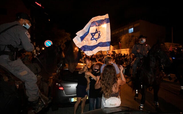 Des agents de police israéliens à cheval bloquent des manifestants lors d'une manifestation des Israéliens contre les mesures de confinement qui, selon certains, visant à limiter le mouvement de protestation anti-Netanyahu, à Tel Aviv,  le 1er octobre 2020 (Crédit :  AP Photo/Sebastian Scheiner)