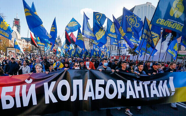 Des manifestants brandissent le drapeau du parti d'extrême droite Svoboda et une banderole disant "Combattre les collaborateurs !" lors d'un défile marquant le Jour du Défenseur de l'Ukraine, à Kiev, le 14 octobre 2020. (AP Photo/Efrem Lukatsky)