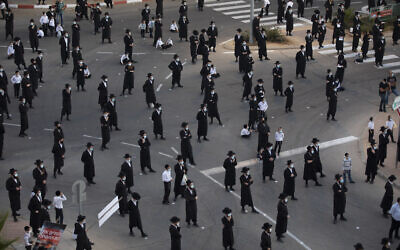 Des Juifs ultra-orthodoxes portent des masques et respectent la distanciation sociale pendant une manifestation organisée à Arad contre ce qu'ils considèrent être des incitations contre leur ville située au sud d'Israël, le 19 octobre 2020. (Crédit : AP/Oded Balilty)