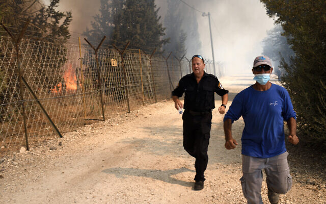 Des hommes échappent aux flammes à Bat Hefer, le 9 octobre 2020. (Crédit : Gili Yaari/Flash90)