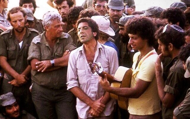 Leonard Cohen, (au centre), se produisant avec le chanteur israélien Matti Caspi, (à la guitare), pour Ariel Sharon, (les bras croisés), et d'autres soldats israéliens, dans le Sinaï, en 1973. (Crédit : Maariv via JTA)