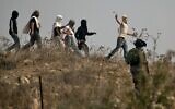 Des soldats israéliens se tiennent prêts alors que des habitants d’implantations israéliens masqués lancent des pierres sur des manifestants palestiniens (non vsisibles) qui se rassemblent lors d'une manifestation contre la construction d'un avant-poste israélien près du village palestinien de Turmusaya et de l’implantation de Shilo, au nord de Ramallah en Cisjordanie, le 17 octobre 2019. (JAAFAR ASHTIYEH/AFP)