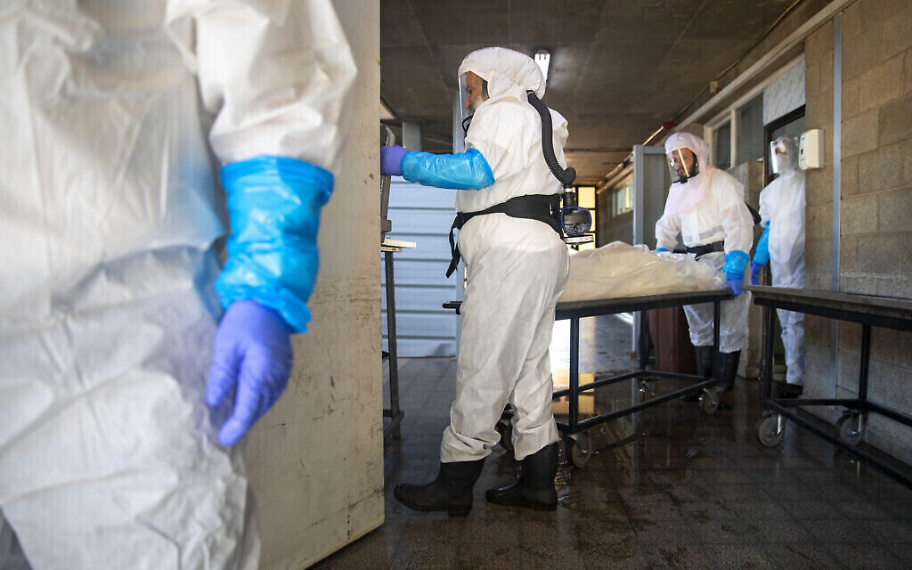 Des membres de la "Hevra Kadisha", la société officielle d'enterrement des Juifs en Israël, préparent un corps avant les funérailles dans une morgue spéciale pour les victimes de COVID-19 à Holon, 23 septembre 2020 (AP Photo/Oded Balilty)