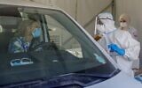 Un ambulancier des services médicaux israéliens du Magen David Adom s'entretient avec un chauffeur dans un centre de test COVID-19 au volant à Jérusalem, le 7 octobre 2020. (AHMAD GHARABLI / AFP)