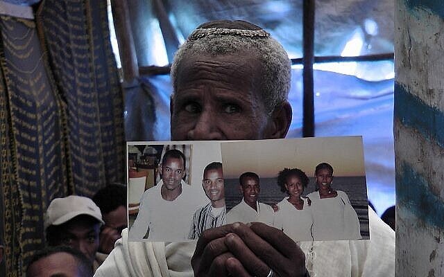 Un fidèle éthiopien à la synagogue d'Addis-Abeba priant et tenant des photos de membres de sa famille vivant en Israël. (Bernard Dichek/ Times of Israel) Un fidèle éthiopien à la synagogue d'Addis-Abeba priant et tenant des photos de membres de sa famille vivant en Israël. (Bernard Dichek/ Times of Israel)