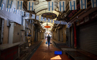 Un homme traverse un marché fermé le premier jour de la fermeture nationale de trois semaines, à Tel Aviv, le 18 septembre 2020 (AP Photo/Oded Balilty)