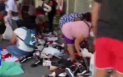 Des passants fouillent les chaussures posées sur un trottoir par un propriétaire de magasin désespéré qui a fait faillite en raison du deuxième confinement à Tel Aviv, le 12 octobre 2020. (Capture d'écran/Treizième chaîne)