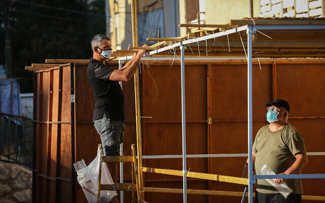 Des Juifs construisent une soucca pour la prochaine fête de Souccot, dans la ville de Safed, au nord du pays, le 29 septembre 2020. (David Cohen/Flash90) Des Juifs construisent une soucca pour la prochaine fête de Souccot, dans la ville de Safed, au nord du pays, le 29 septembre 2020. (David Cohen/Flash90)