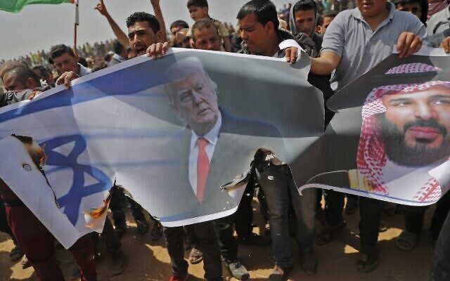 Les Palestiniens s'apprêtent à incendier un drapeau israélien et des portraits du président américain Donald Trump et du prince héritier saoudien Mohammed ben Salmane lors d'une manifestation contre la barrière frontalière avec Israël, à l'est de Khan Younès, au sud de Gaza, le 13 avril 2018. (Crédit : AFP PHOTO / Thomas COEX)