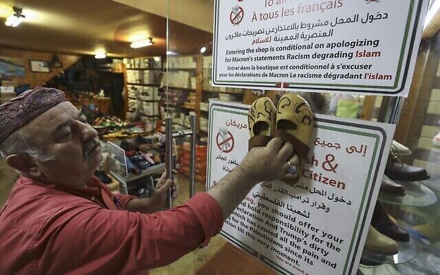 Un cordonnier palestinien, Imad Mohammad, et ses chaussures ornées des noms des présidents français et américains en calligraphie arabe, dans sa boutique de Ramallah, le 30 octobre 2020. (Crédit : Abbas Momani/AFP)