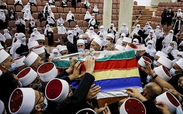 Des membres de la communauté druze portent le corps de feu le chef spirituel Cheikh Abu Zain al-Din Hassan Halabi, lors de ses funérailles, malgré l'interdiction nationale des rassemblements de masse en raison du coronavirus, dans la ville frontalière de Majdal Shams, sur le plateau du Golan, le 30 octobre 2020. (Crédit : Jalaa Marey/AFP) Des membres de la communauté druze portent le corps de feu le chef spirituel Cheikh Abu Zain al-Din Hassan Halabi, lors de ses funérailles, malgré l'interdiction nationale des rassemblements de masse en raison du coronavirus, dans la ville frontalière de Majdal Shams, sur le plateau du Golan, le 30 octobre 2020. (Crédit : Jalaa Marey/AFP)