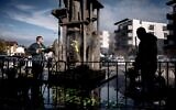 Un homme nettoie un mémorial du génocide arménien à Décines-Charpieu, près de Lyon, le 1er novembre 2020, sur lequel un message anti-Arméniens a été tagué par des nationalistes turcs. (Crédit : JEFF PACHOUD / AFP)