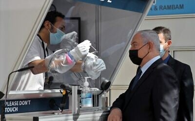 Le Premier ministre Benjamin Netanyahu, portant un masque, assiste à une démonstration de prélèvement de coronavirus par écouvillonnage lors de l'inauguration d'un centre de dépistage rapide du coronavirus COVID-19 à l'aéroport international Ben Gurion de Lod, le 9 novembre 2020. (ATEF SAFADI / POOL / AFP) Le Premier ministre Benjamin Netanyahu, portant un masque, assiste à une démonstration de prélèvement de coronavirus par écouvillonnage lors de l'inauguration d'un centre de dépistage rapide du coronavirus COVID-19 à l'aéroport international Ben Gurion de Lod, le 9 novembre 2020. (ATEF SAFADI / POOL / AFP)