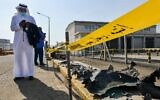Un homme, masqué en raison de la pandémie de coronavirus COVID-19, parcourt son téléphone alors qu'il se tient près des débris suite à l'attaque de l'installation pétrolière Saudi Aramco à Djeddah, en Arabie Saoudite, le 24 novembre 2020. (FAYEZ NURELDINE / AFP)