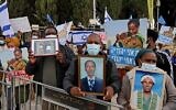 Des membres de la communauté éthiopienne israélienne brandissent des photos de leurs proches devant le bureau du Premier ministre à Jérusalem, le 25 novembre 2020. (Menahem Kahana / AFP)