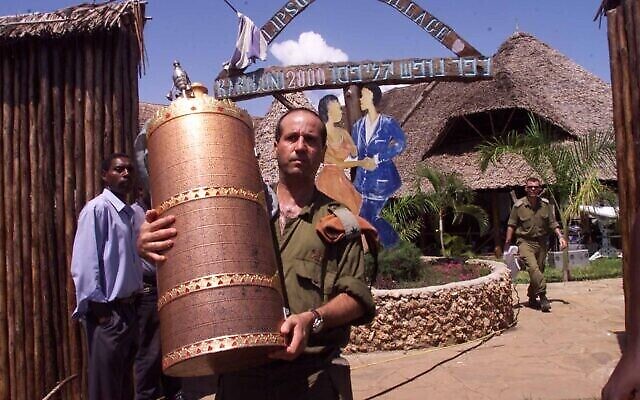 Un soldat israélien enlève un rouleau de la Torah de l'hôtel Paradise, propriété d'Israël, le vendredi 29 novembre 2002, à Kikambala, près de Mombassa, au Kenya. L'explosion de l'hôtel Paradise a tué 10 Kenyans, trois Israéliens et les trois kamikazes. (AP Photo/Karel Prinsloo)