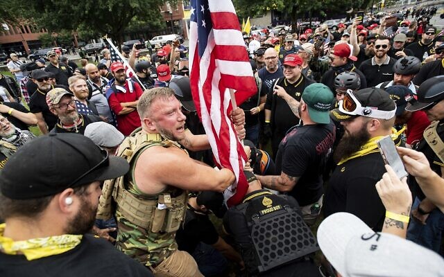Joseph Oakman et ses camarades Proud Boys plantent un drapeau dans le Tom McCall Waterfront Park lors d'un rassemblement à Portland, Oregon, le 17 août 2019. (AP Photo/Noah Berger) Joseph Oakman et ses camarades Proud Boys plantent un drapeau dans le Tom McCall Waterfront Park lors d'un rassemblement à Portland, Oregon, le 17 août 2019. (AP Photo/Noah Berger)