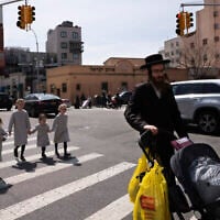Illustration : Un homme juif ultra-orthodoxe se promène avec ses filles dans le quartier de Williamsburg, à Brooklyn, le 7 avril 2020. (Crédit : Mark Lennihan/AP Photo)