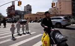 Illustration : Un homme juif ultra-orthodoxe se promène avec ses filles dans le quartier de Williamsburg, à Brooklyn, le 7 avril 2020. (Crédit : Mark Lennihan/AP Photo)