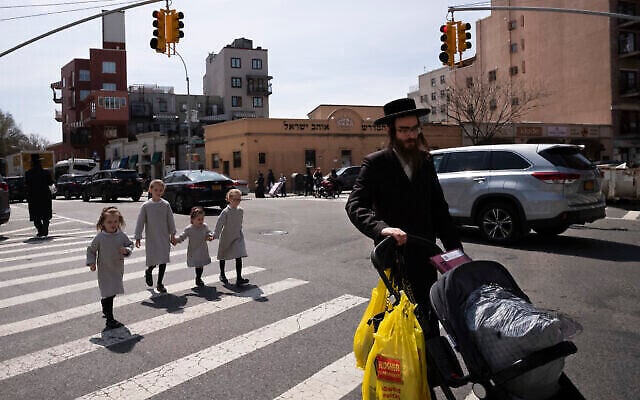 Illustration : Un homme juif ultra-orthodoxe se promène avec ses filles dans le quartier de Williamsburg, à Brooklyn, le 7 avril 2020. (Crédit : Mark Lennihan/AP Photo)