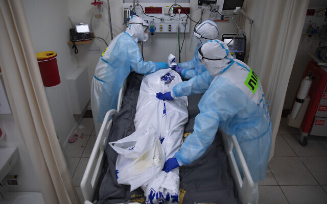 Des personnels médicaux portant des équipements de protection recouvrent la dépouille d'un homme décédé des suites de la COVID-19 dans l'unité pour soins intensifs mise en place pour les malades du coronavirus au centre médical Shaare Zedek de Jérusalem, le 23 novembre 2020. (Crédit : AP Photo/Oded Balilty) Des personnels médicaux portant des équipements de protection recouvrent la dépouille d'un homme décédé des suites de la COVID-19 dans l'unité pour soins intensifs mise en place pour les malades du coronavirus au centre médical Shaare Zedek de Jérusalem, le 23 novembre 2020. (Crédit : AP Photo/Oded Balilty)