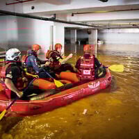 Des pompiers israéliens à la recherche  de possibles victimes dans un parking inondé à Ness Ziona, le 21 novembre 2020 (Crédit : Yossi Aloni/Flash90)