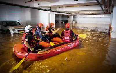 Des pompiers israéliens à la recherche  de possibles victimes dans un parking inondé à Ness Ziona, le 21 novembre 2020 (Crédit : Yossi Aloni/Flash90)