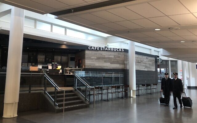 Des membres de l'équipage d'un avion passent devant un café Starbucks vide à l'aéroport international Pierre Elliott Trudeau à Montréal, le 17 mars 2020. (Crédit : JOCELYNE ZABLIT/AFP via Getty Images) Des membres de l'équipage d'un avion passent devant un café Starbucks vide à l'aéroport international Pierre Elliott Trudeau à Montréal, le 17 mars 2020. (Crédit : JOCELYNE ZABLIT/AFP via Getty Images)
