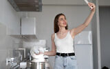 Illustration : Une femme cuisine et partage la scène par téléphone portable. Selon des scientifiques israéliens, les gens pourront bientôt transmettre les odeurs. (Andrii Lysenko via iStock par Getty Images)