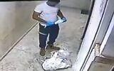 Un employé des services d'urgence du  Magen David Adom remet son masque après avoir craché sur des images de Jésus et Marie dans un immeuble résidentiel de Jaffa, le 15 novembre 2020. (Capture d'écran/Kan)