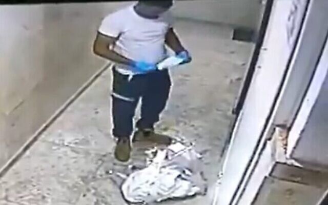 Un employé des services d'urgence du Magen David Adom remet son masque après avoir craché sur des images de Jésus et Marie dans un immeuble résidentiel de Jaffa, le 15 novembre 2020. (Capture d'écran/Kan) Un employé des services d'urgence du Magen David Adom remet son masque après avoir craché sur des images de Jésus et Marie dans un immeuble résidentiel de Jaffa, le 15 novembre 2020. (Capture d'écran/Kan)
