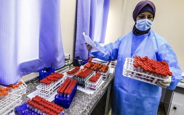 Une technicienne sanitaire s’occupe d’échantillons PCR collectés au laboratoire central du ministère palestinien de la Santé à Gaza, le 7 décembre 2020. (Crédit : MAHMUD HAMS / AFP) Une technicienne sanitaire s’occupe d’échantillons PCR collectés au laboratoire central du ministère palestinien de la Santé à Gaza, le 7 décembre 2020. (Crédit : MAHMUD HAMS / AFP)