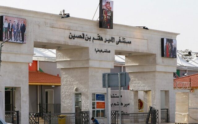 Un petit garçon assis devant l'entrée principale de l'hôpital de campagne  Prince Hashem bin Hussein, premier hôpital consacré à la Covid-19 dans le pays, à Zarqa, à 25 kilomètres de la capitale Amman, le 8 décembre 2020. (Crédit :  Khalil MAZRAAWI / AFP)