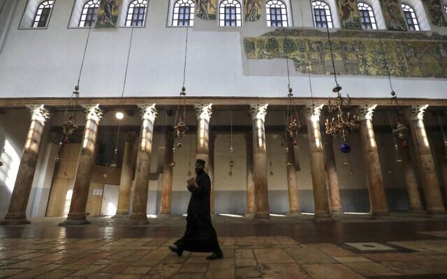 Un prêtre orthodoxe se promène dans l'église de la Nativité, dans la ville de Bethléem en Cisjordanie, le 20 décembre 2020. (Crédit : HAZEM BADER / AFP)