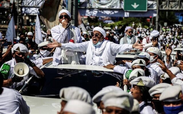 Le leader musulman Rizieq Shihab, chef de l'organisation indonésienne radicale du Front des défenseurs de l'islam, alpague ses partisans lors de l’inauguration d’une mosquée à Bogor, le 13 novembre 2020. (Crédit : ADITYA SAPUTRA / AFP) Le leader musulman Rizieq Shihab, chef de l'organisation indonésienne radicale du Front des défenseurs de l'islam, alpague ses partisans lors de l’inauguration d’une mosquée à Bogor, le 13 novembre 2020. (Crédit : ADITYA SAPUTRA / AFP)