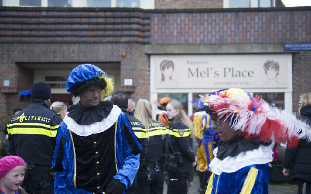 Un homme déguisé en Zwart Piet divertit les enfants sous la protection de la police dans le nord d'Amsterdam, le 16 novembre 2019. (Crédit : Cnaan Liphshiz/JTA)