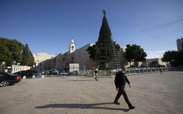 Un homme marche devant l'église de la Nativité, traditionnellement considérée comme le lieu de naissance de Jésus-Christ, dans la ville de Bethléem, en Cisjordanie, le 23 novembre 2020. (Crédit : AP / Majdi Mohammed) Un homme marche devant l'église de la Nativité, traditionnellement considérée comme le lieu de naissance de Jésus-Christ, dans la ville de Bethléem, en Cisjordanie, le 23 novembre 2020. (Crédit : AP / Majdi Mohammed)