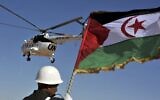 Un soldat tient un drapeau sahraoui alors qu'un hélicoptère des Nations unies survole le camp de réfugiés de Smara près de Tindouf, dans le sud-ouest de l'Algérie, le 5 mars 2016. (Crédit : AP Photo/Toufik Doudou)