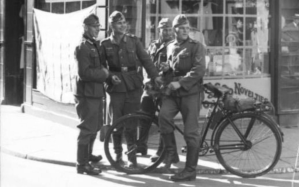 Soldats allemands debout dans la rue King, à Saint Helier, à Charing Cross (aujourd'hui site du monument de la Croix de la Reine) pendant l'occupation de l'île anglo-normande de Jersey pendant la Seconde Guerre mondiale. (Bundesarchiv Bild)