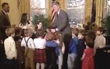 Capture d'écran d'une vidéo de 1993 montrant le président américain Bill Clinton saisissant les cheveux d'Ilana Kattan pour les empêcher de s’enflammer, après avoir vu qu'ils avaient pris feu à la menorah que la classe venait de l'aider à allumer à la Maison Blanche. (Bibliothèque présidentielle Clinton sur YouTube via JTA)
