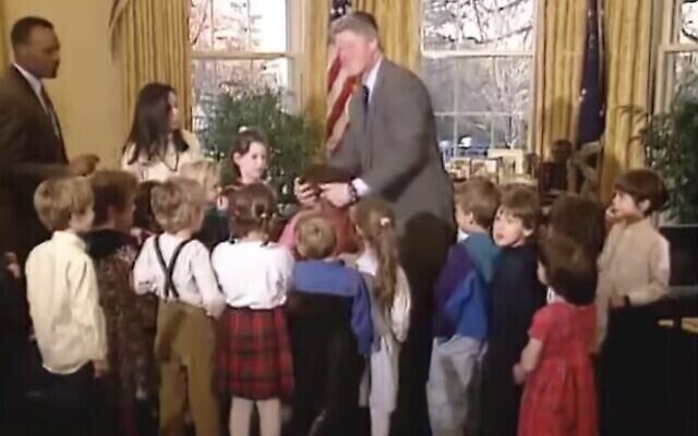Capture d'écran d'une vidéo de 1993 montrant le président américain Bill Clinton saisissant les cheveux d'Ilana Kattan pour les empêcher de s’enflammer, après avoir vu qu'ils avaient pris feu à la menorah que la classe venait de l'aider à allumer à la Maison Blanche. (Bibliothèque présidentielle Clinton sur YouTube via JTA) Capture d'écran d'une vidéo de 1993 montrant le président américain Bill Clinton saisissant les cheveux d'Ilana Kattan pour les empêcher de s’enflammer, après avoir vu qu'ils avaient pris feu à la menorah que la classe venait de l'aider à allumer à la Maison Blanche. (Bibliothèque présidentielle Clinton sur YouTube via JTA)